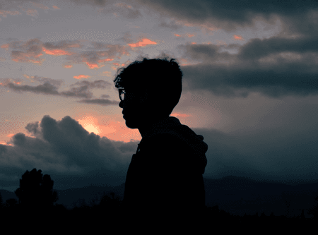 Silhouette of a man against a dark, cloudy sky